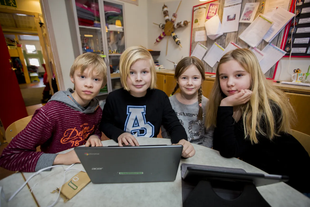 En grupp grundskoleelever sitter och jobbar vid en bärbar dator.