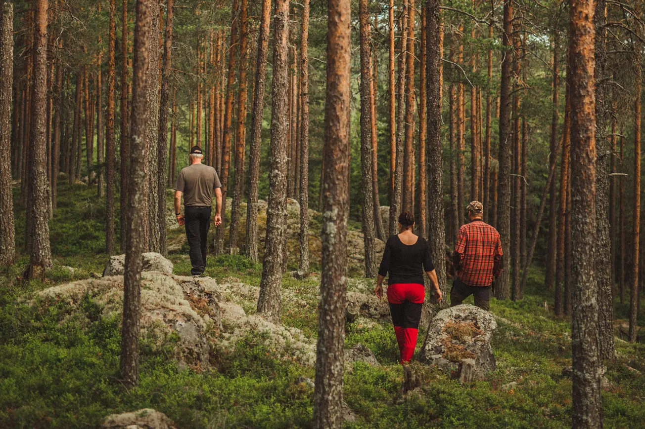 Tre personer som går genom en skog.