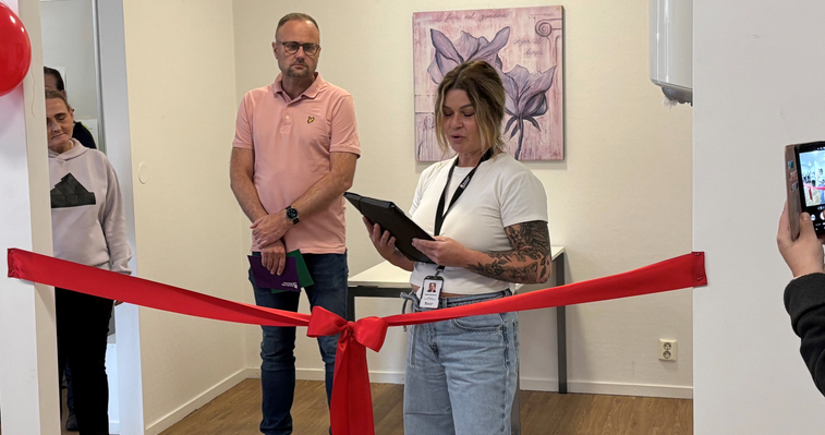 Personer som står bakom ett rött band på en invigning