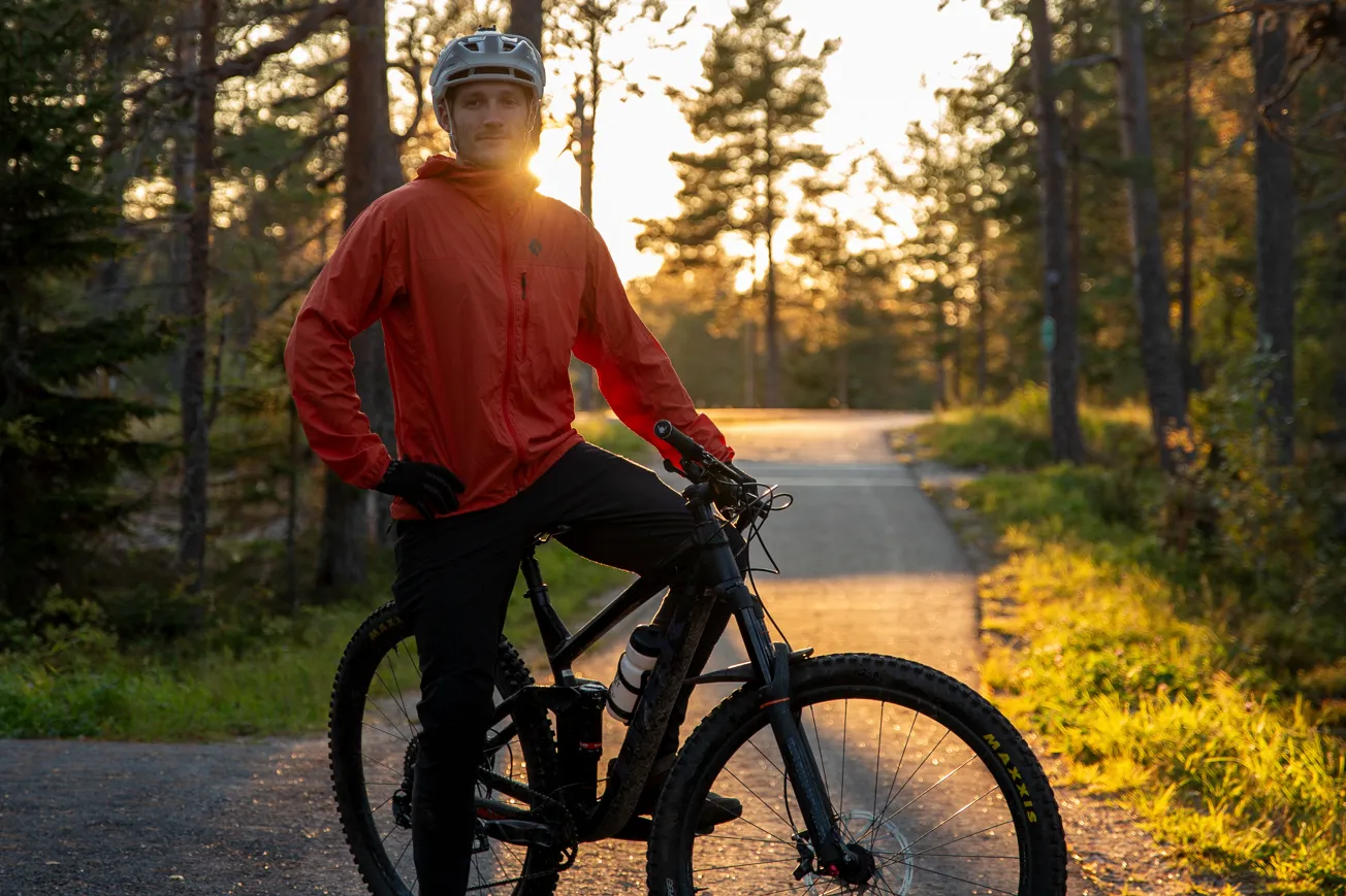 En man som står på en cykel vid sidan av en väg.