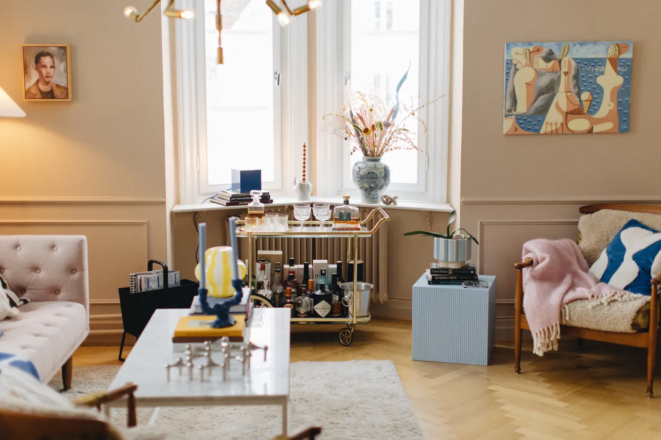 Ett sobert vardagsrum inrett med designprylar och färgstarka detaljer.
