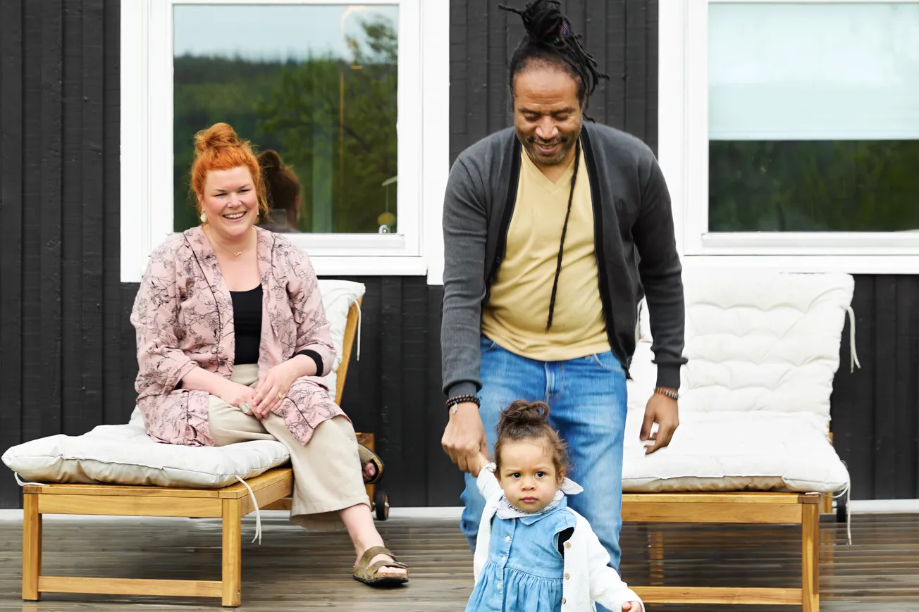 En man och en kvinna som står på en veranda med ett barn.