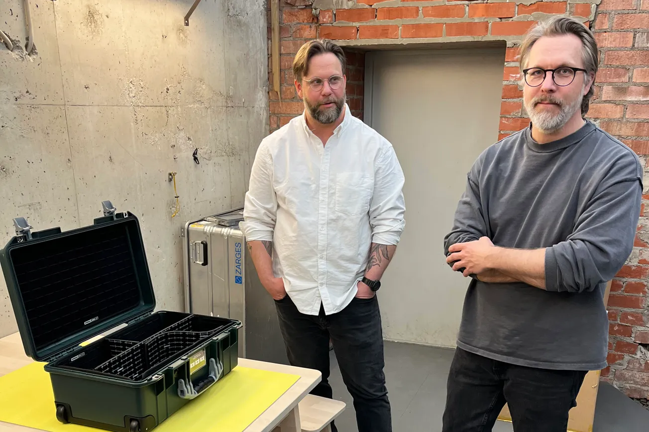Två män står i en verkstad och visar upp deras produkt. En väska.