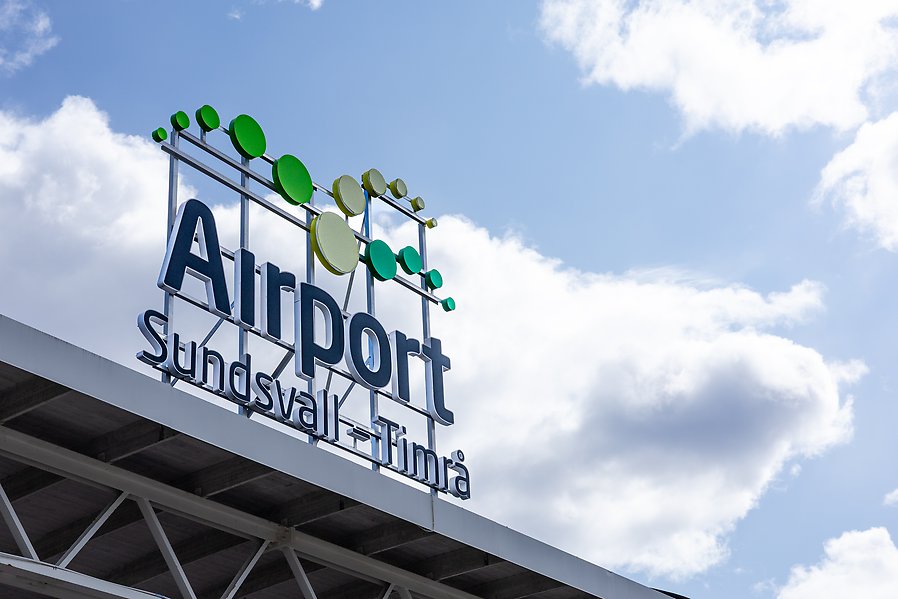 En skylt det står "airport Sunsdvall - Timrå" på med himmel som bakgrund.