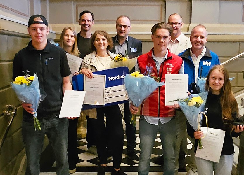 En grupp av människor står i en trapp och håller i blommor och priser.