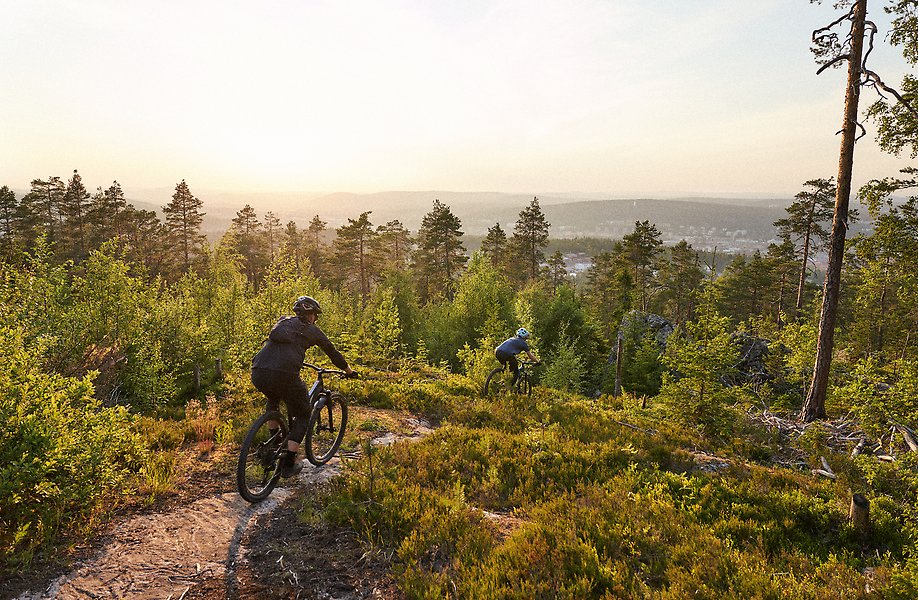Två personer cyklar på Södra Berget. Utsikt över Sundsvalls stad.