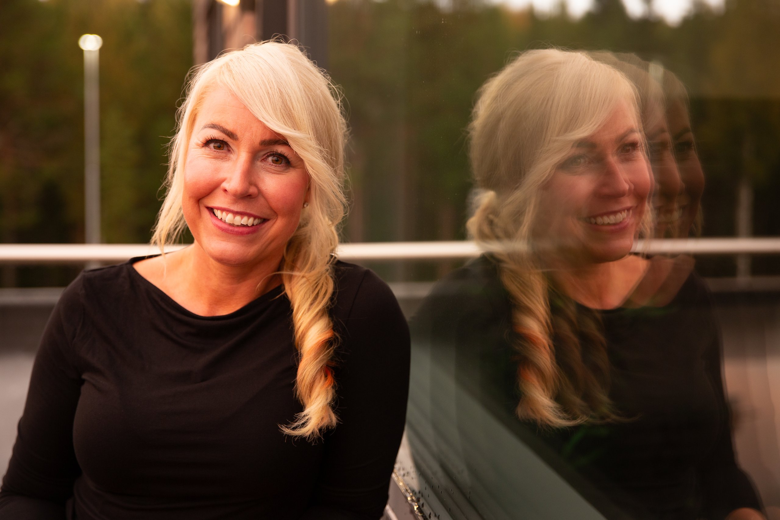 Kvinna som står med armen mot ett räcke och ler in mot kameran