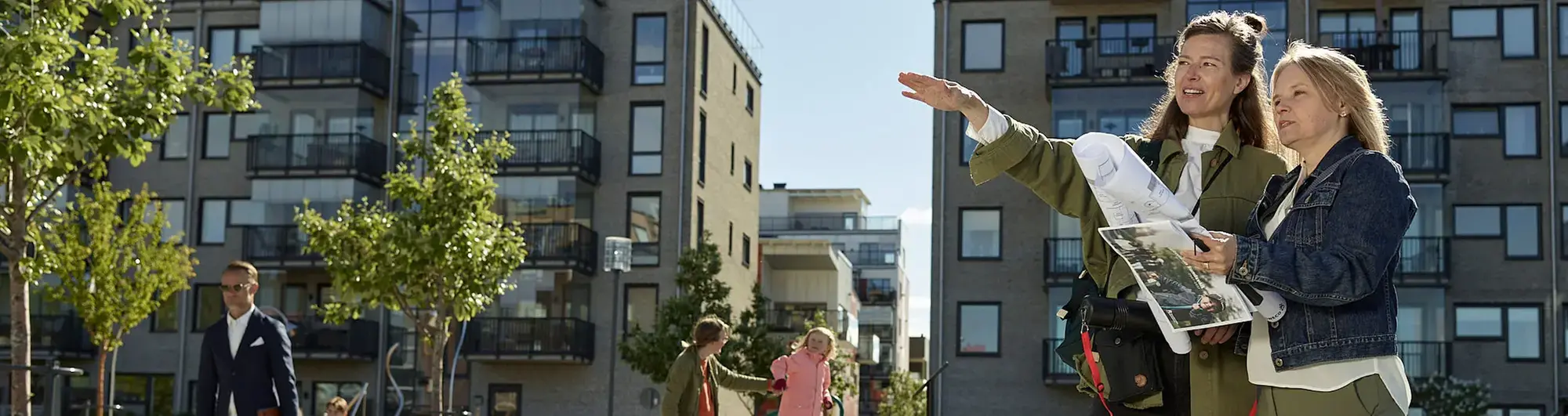 Två kvinnor står utomhus med en karta framför sig
