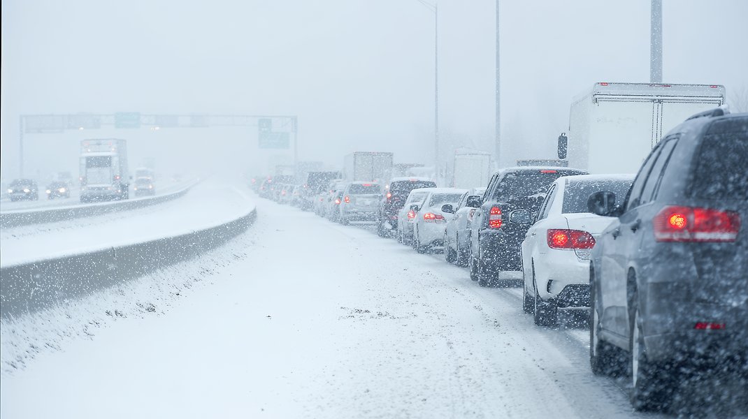 Lång bilkö på motorväg, det faller mycket snö. 