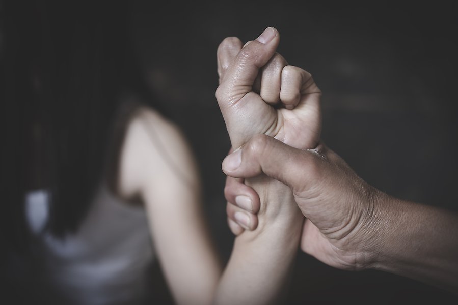 En hand håller hårt och kontrollerande i en kvinnas hand.